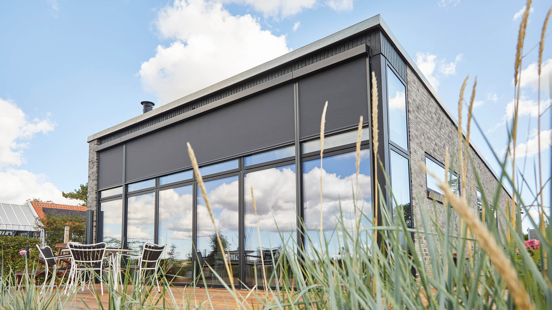 Stort moderne hus med udvendige screens i sort.