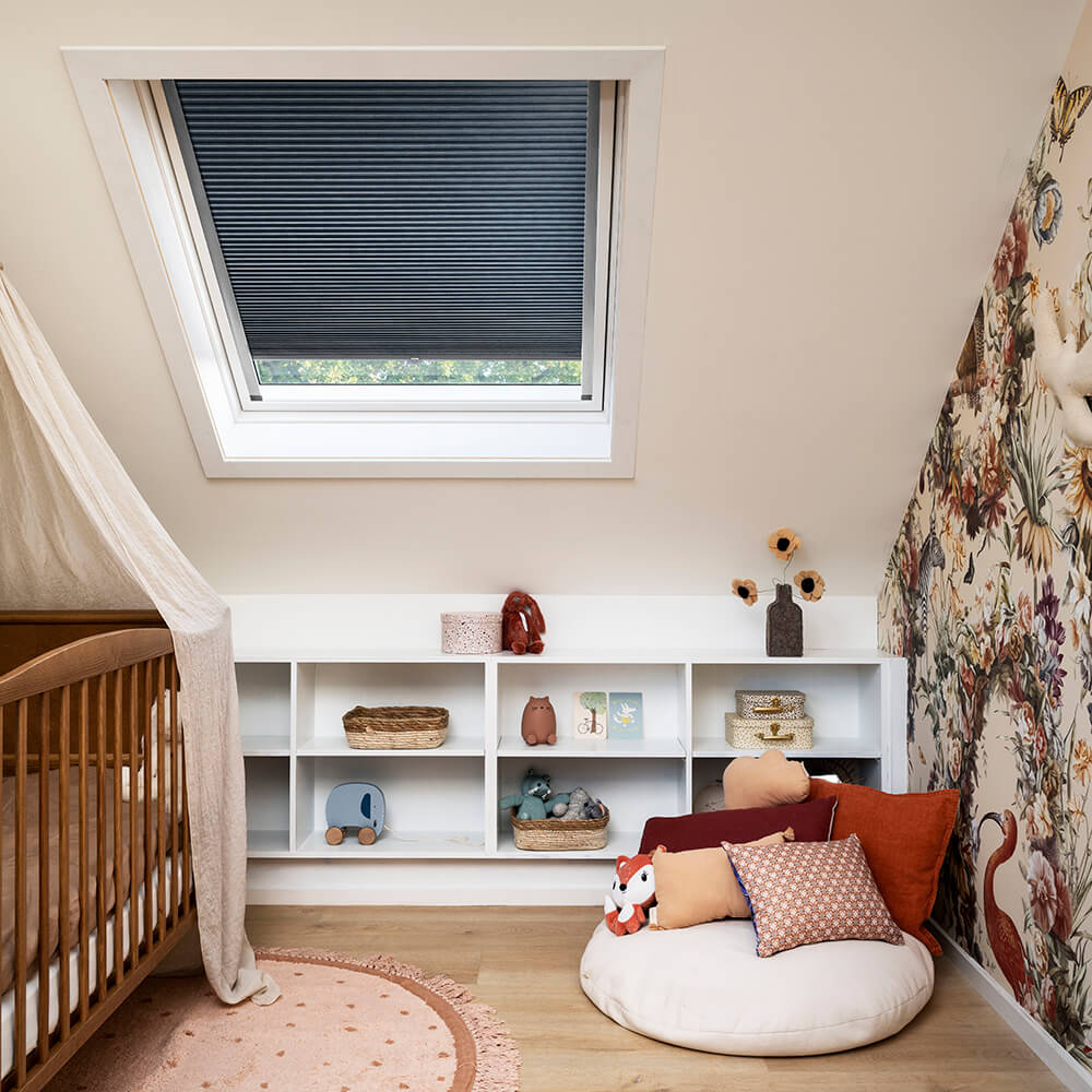 Dupligardin med mørklægning i et børneværelse med skråvindue.